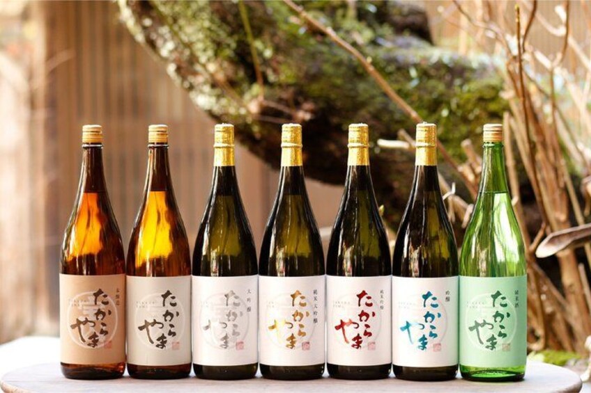 Six bottles of sake with different labels, arranged on a table. 5