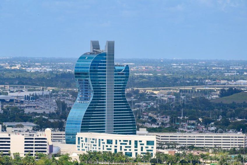 A modern skyscraper with a unique curved design, surrounded by a cityscape and greenery. 4