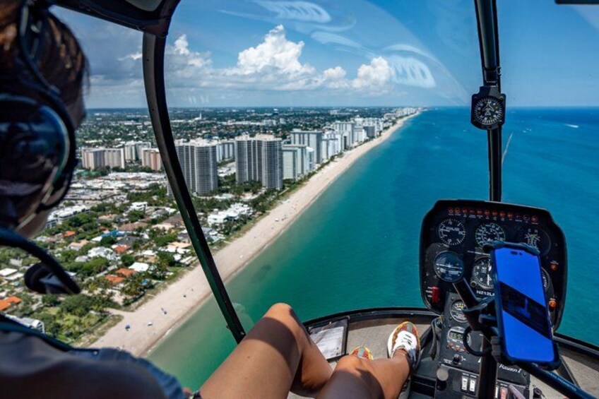 A helicopter cockpit with a view of a beach and cityscape. 1