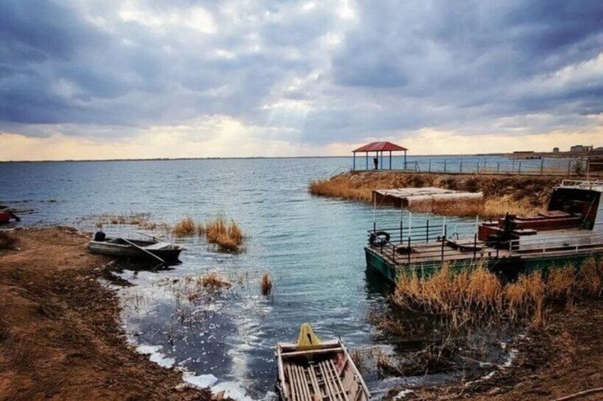 A calm lake with boats, a dock, and a red umbrella. 5