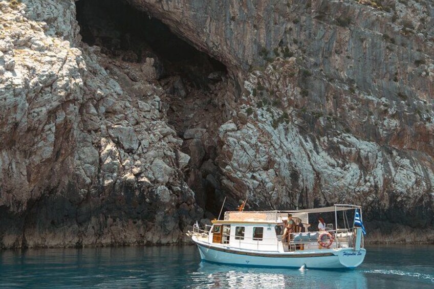 A boat near a rocky cliff with a cave entrance. 2