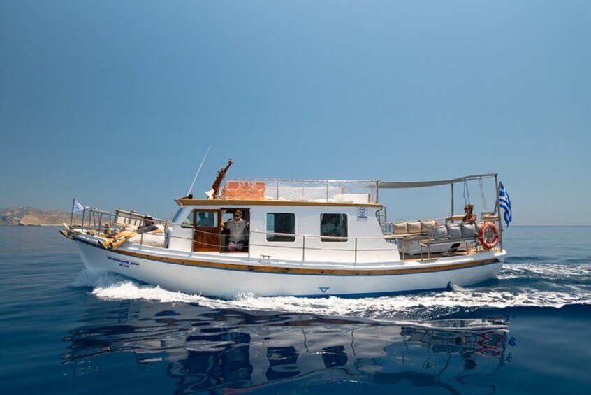 A white boat with a cabin and a blue flag, moving through calm waters. 3