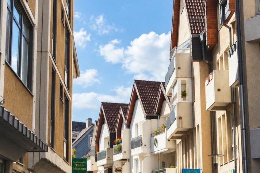 A row of residential buildings with pitched roofs and balconies, under a clear sky. 4