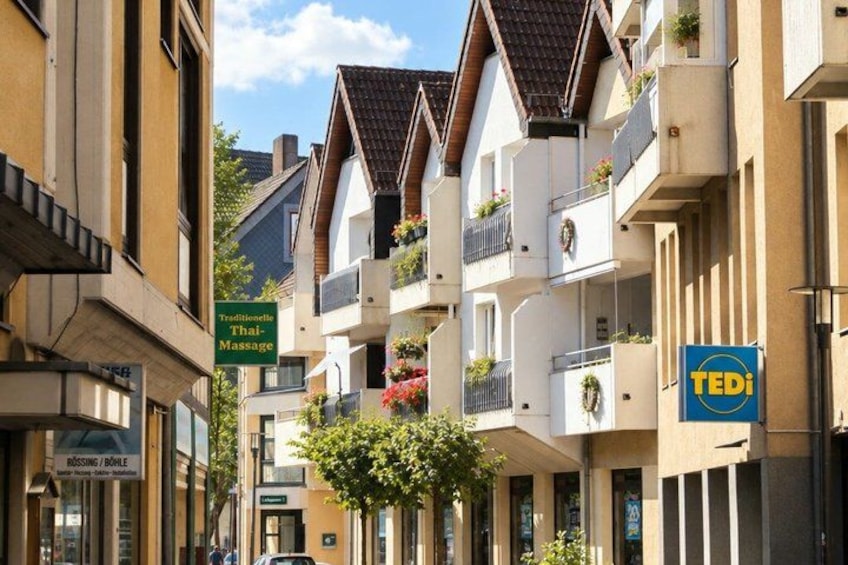 A street with traditional Thai massage sign, a Tedi store, and residential buildings with balconies. 3