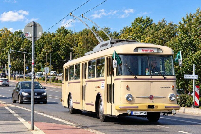 A vintage tram at a street intersection with traffic lights and a pedestrian crossing. 2