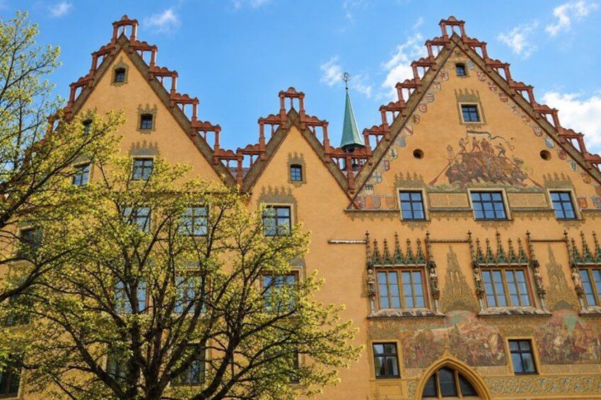 A building with a yellow facade, pointed roof, and decorative windows. 4