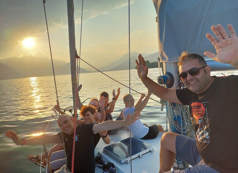 A group of people on a sailboat with the sun setting in the background. 2