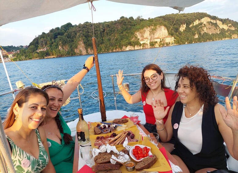 A group of people on a boat with a table of food and drinks, surrounded by water and cliffs. 5