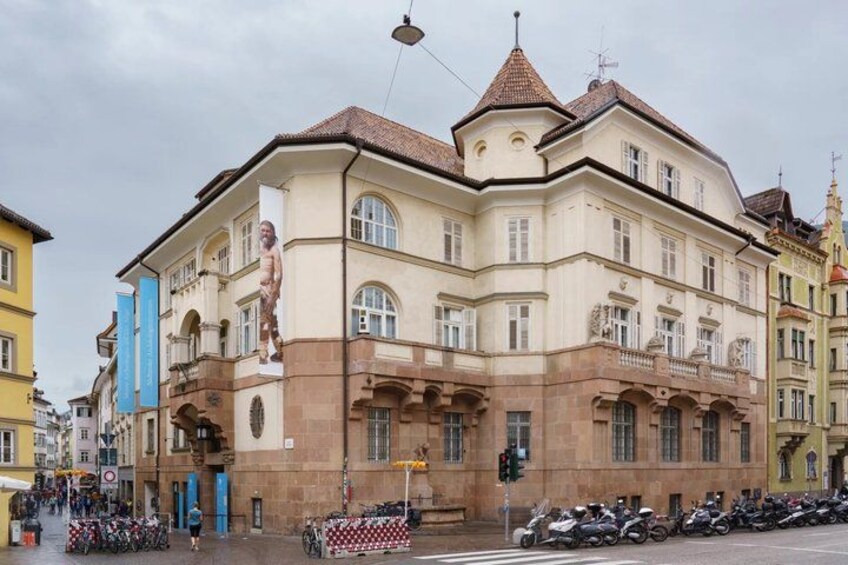 A historic building with a statue, parked motorcycles, and a street with pedestrians. 2