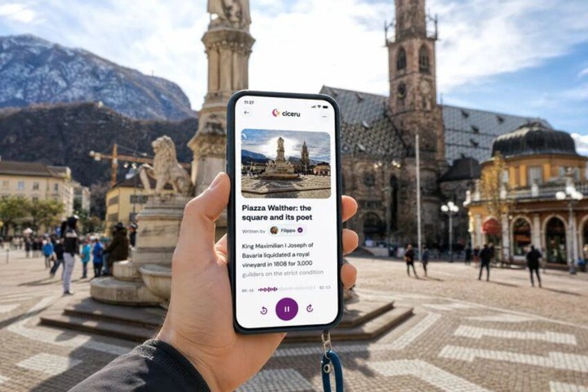 A smartphone displaying an article about Piazza Walther, with a historic square and a church in the background. 1