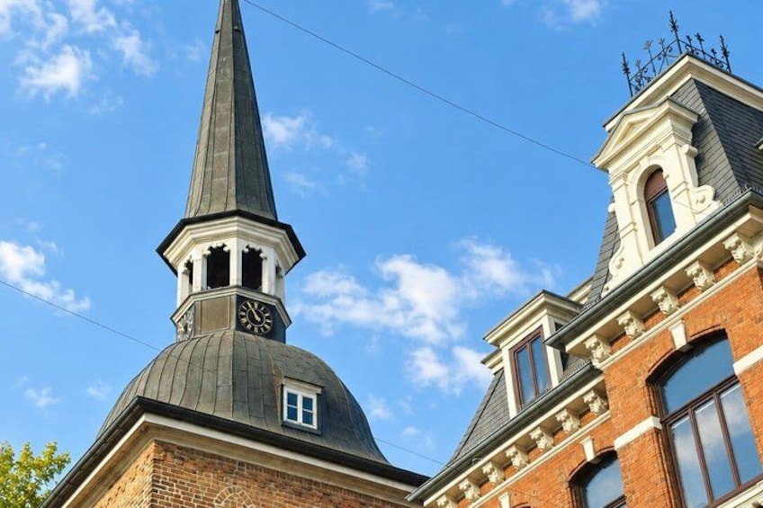 A church steeple with a clock, a brick building, and a clear blue sky. 4