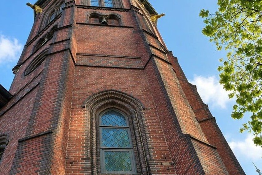 A tall brick church tower with arched windows and a clock. 2