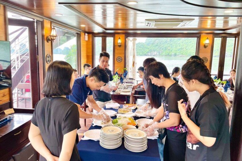 A group of people serving food in a boat with a view of the water outside. 2