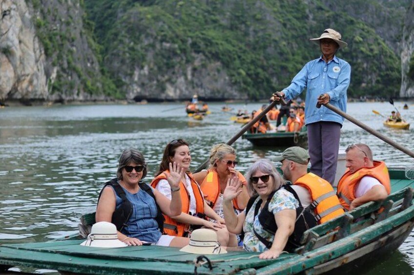 A group of people in a green boat on a body of water, wearing life jackets, with a guide standing at the stern. 5