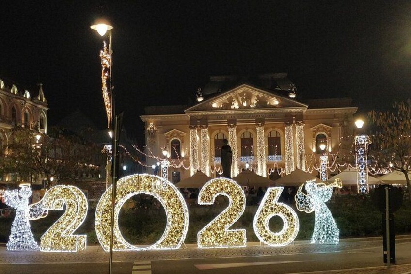 Illuminated numbers '2026' in front of a classical building at night. 1