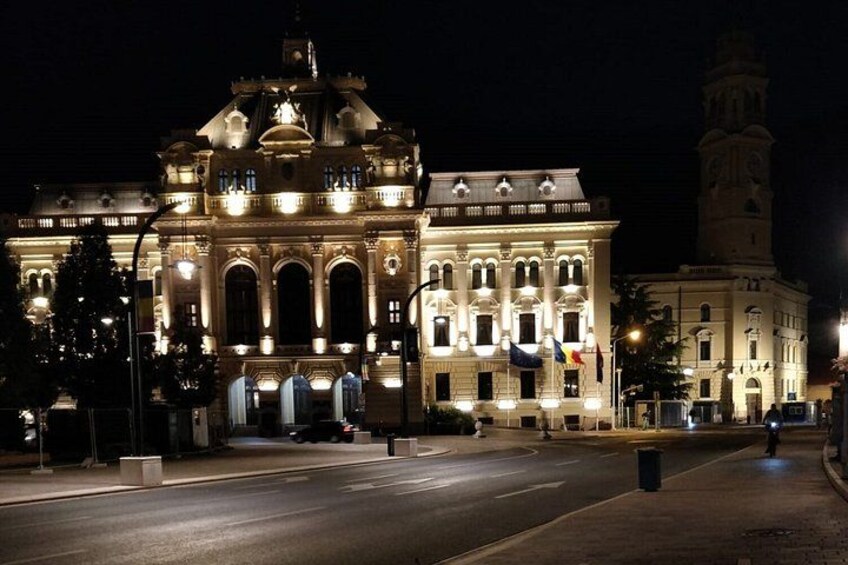A grand illuminated building with arched windows and a clock tower at night. 3