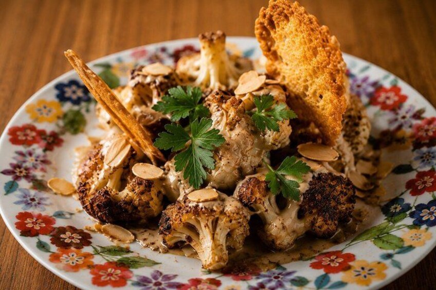 A plate of roasted cauliflower with almonds and parsley garnish. 3
