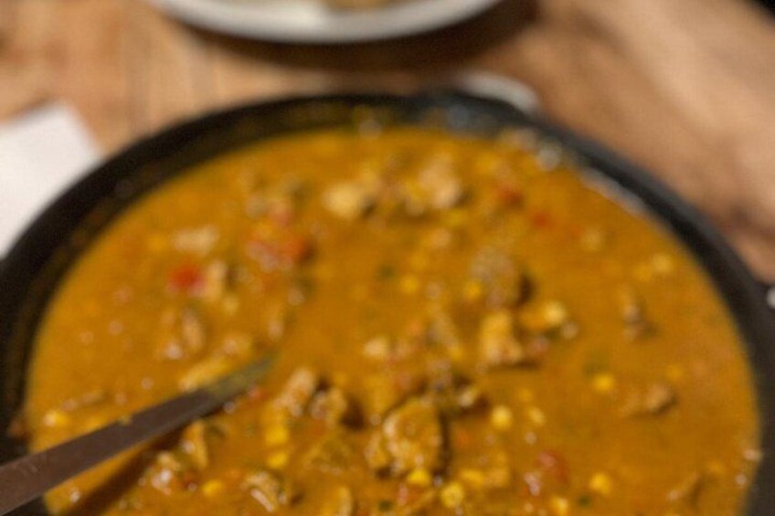 A bowl of curry with visible pieces of meat and vegetables. 4