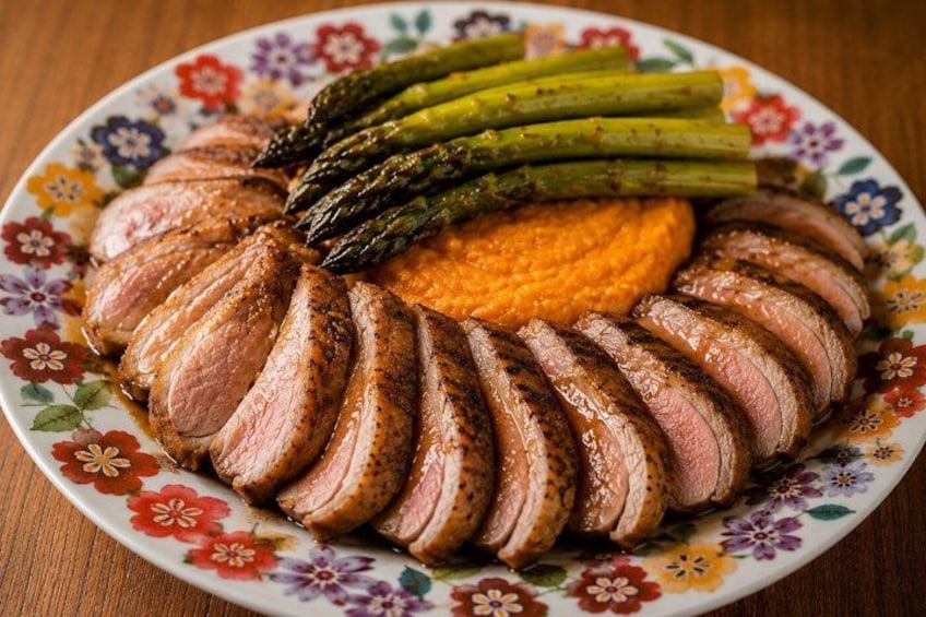 A plate of sliced meat, asparagus, and a carrot puree. 1