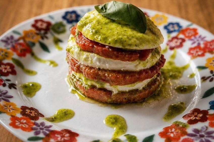 A layered sandwich with pesto on a floral plate. 2