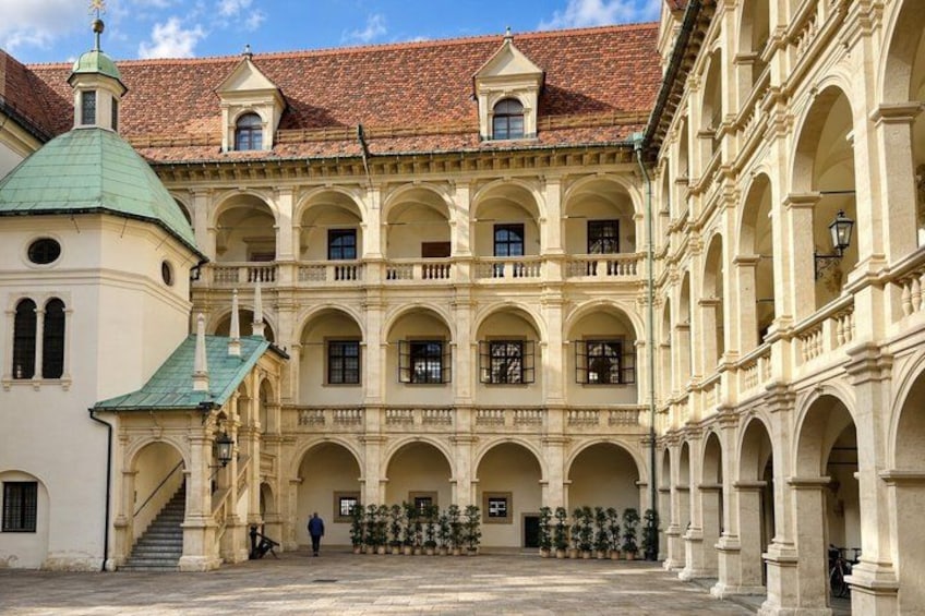 A courtyard with a central open space surrounded by buildings with arched windows and a tiled roof. 3