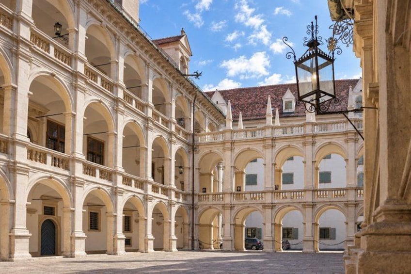 A historic courtyard with arches, a tiled roof, and a street lamp. 2