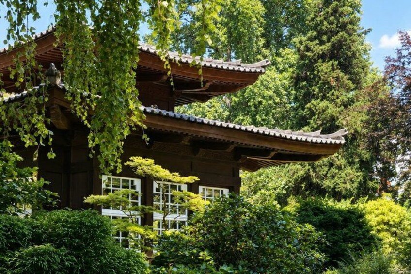 A traditional Japanese building with a curved roof, surrounded by lush greenery and trees. 2