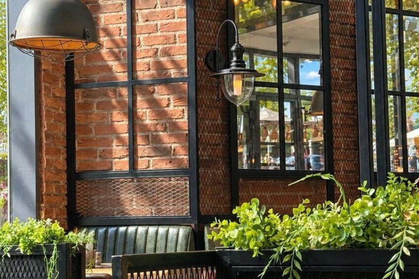 A brick building with a large window, a metal lamp, and a bench. 4