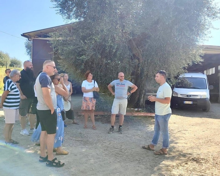 A group of people standing outdoors near a building and a parked car. 1