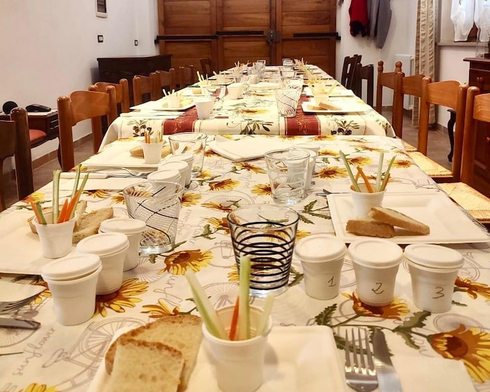 A long dining table set with plates, cups, and cutlery, covered with a floral tablecloth. 4