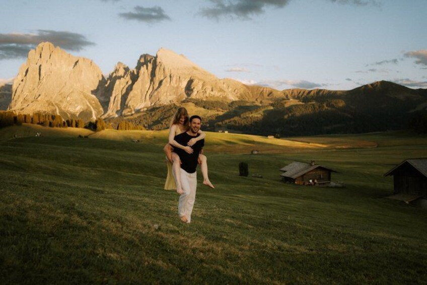A couple in a grassy field with mountains in the background. 2