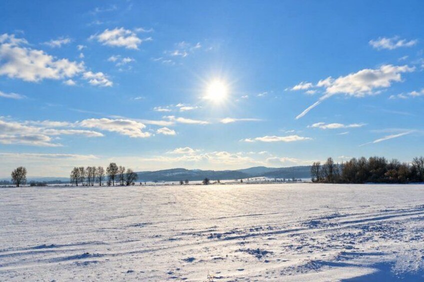 A snowy field with a clear sky and the sun shining. 2