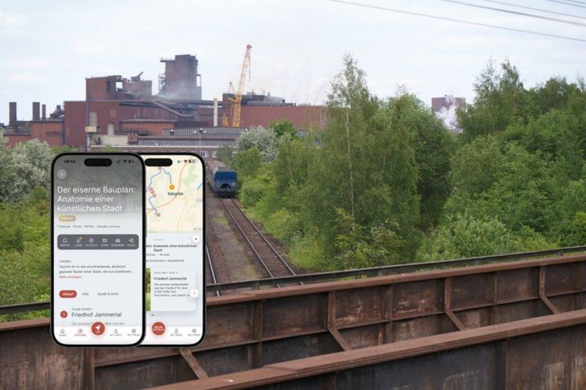 A smartphone displaying a map with a train on tracks, surrounded by greenery and industrial buildings. 1