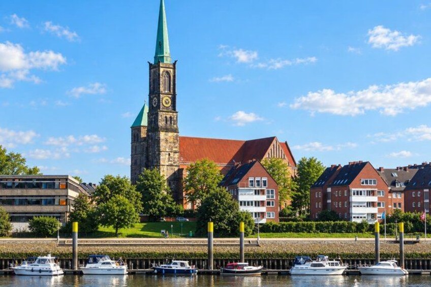 A church with a tall steeple, a red-roofed building, and several boats docked by the water. 4