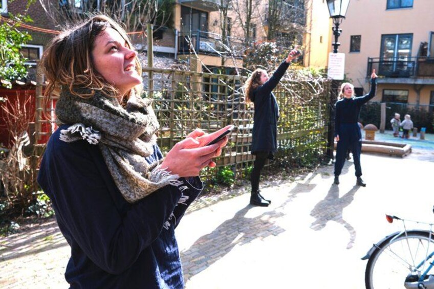 A person holding a phone, another person pointing, and a bicycle in an outdoor setting. 1