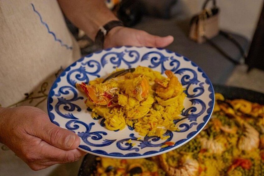 A person holding a plate with yellow rice and shrimp. 5