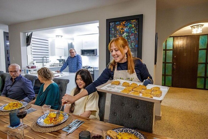 A family dining in a modern kitchen with a woman serving food. 4