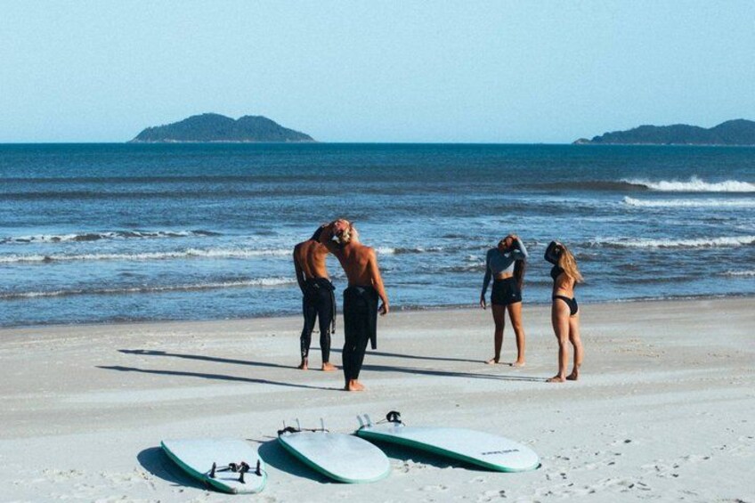A beach with three people, two surfboards, and a distant island. 3