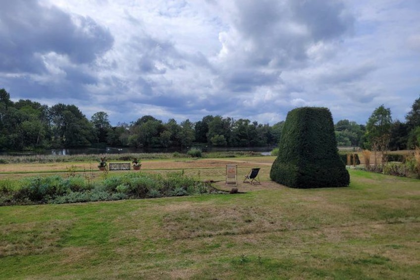 A park with a large topiary, a bench, and a chair. 2