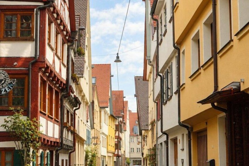 A narrow street lined with colorful buildings, a street lamp, and a clear sky. 4