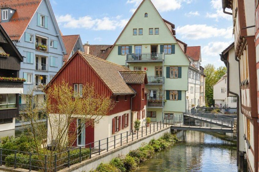 A canal with buildings on either side, a red house in the foreground, and a bridge in the background. 3