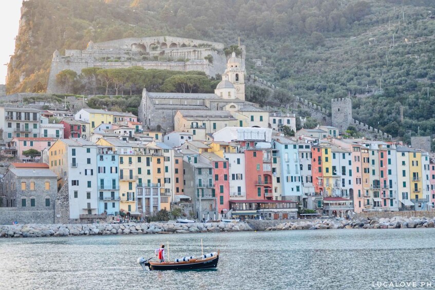Una località costiera con edifici colorati, un forte storico e una barca sull'acqua. 5