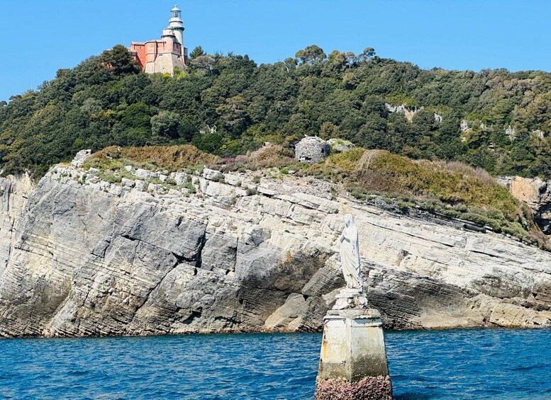 Paesaggio costiero con una scogliera rocciosa, un faro e una statua. 4