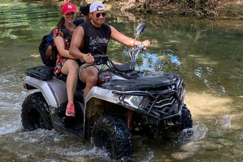 Two people on an ATV in a shallow water body. 2