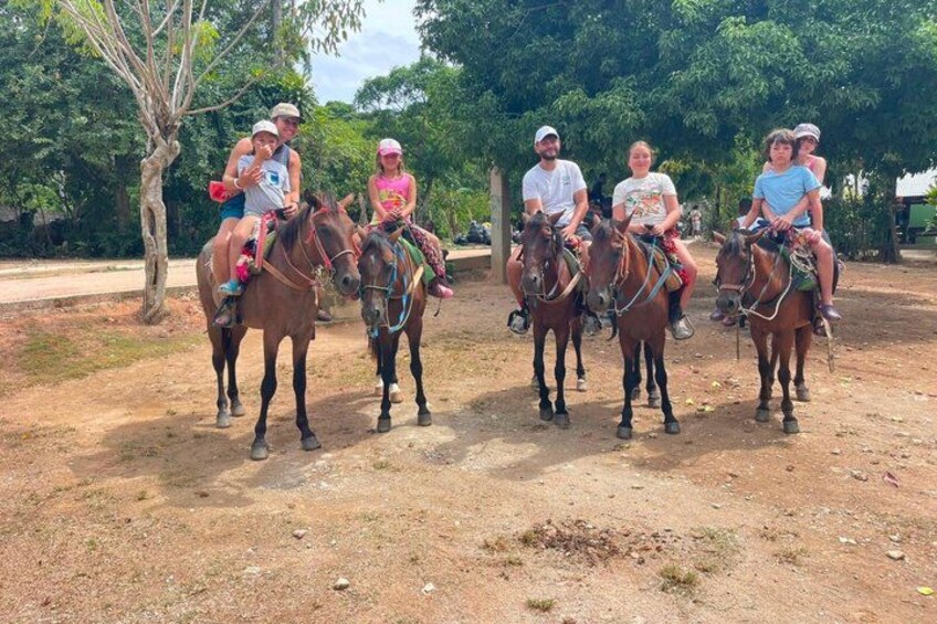 A group of people riding horses on a dirt path with trees in the background. 3
