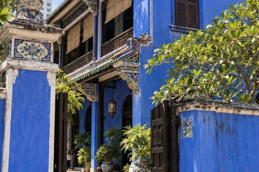 A blue building with ornate decorations, a balcony, and potted plants. 3