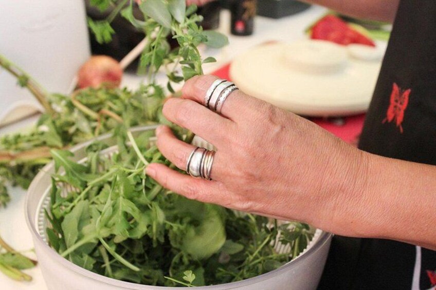 A person handling leafy greens in a bowl. 4