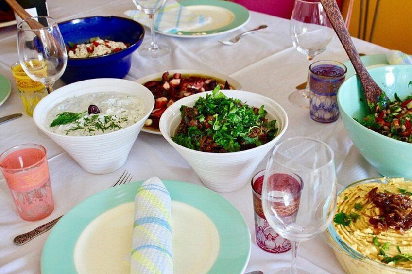 A table with various dishes, glasses of wine, and a blue bowl. 5