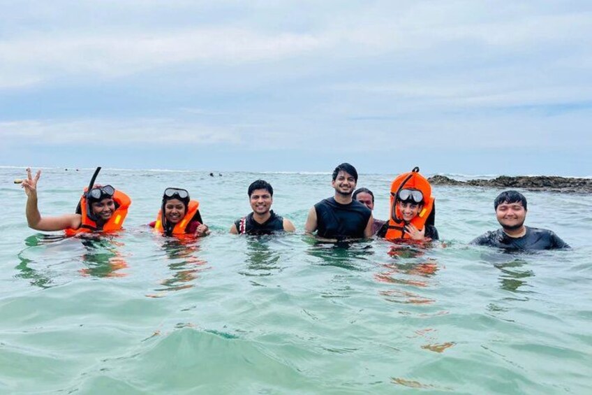 A group of people in a body of water wearing life jackets. 4