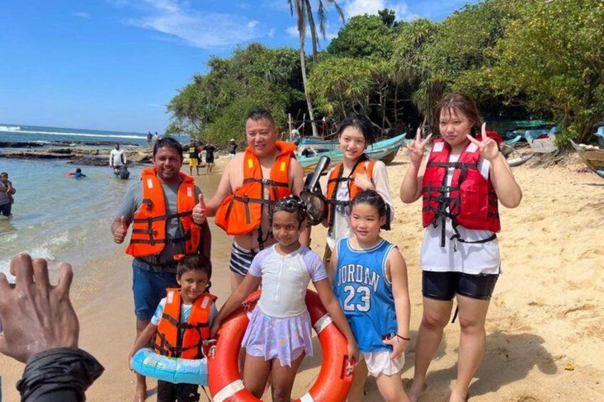 A group of people on a beach with life jackets, a child in a blue jersey, and a lifebuoy. 3